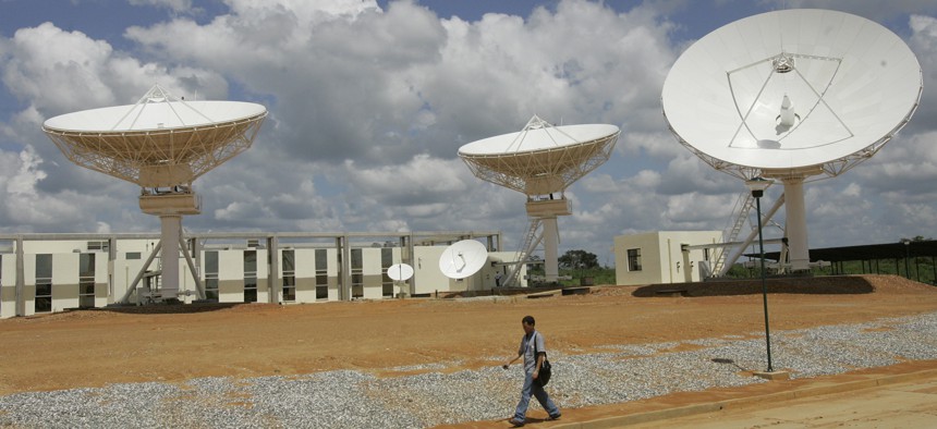 In this Oct. 28, 2008 file photo, a man walks past a satellite dish station in El Sombrero, Venezuela. 