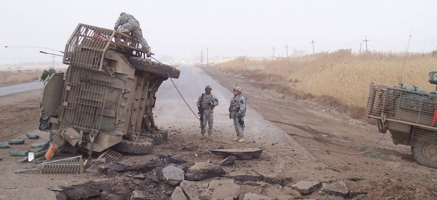 A Stryker fighting vehicle lies on its side after surviving a buried IED blast in Iraq in 2007.
