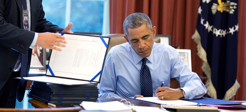 President Barack Obama signs bills in the Oval Office in 2014.