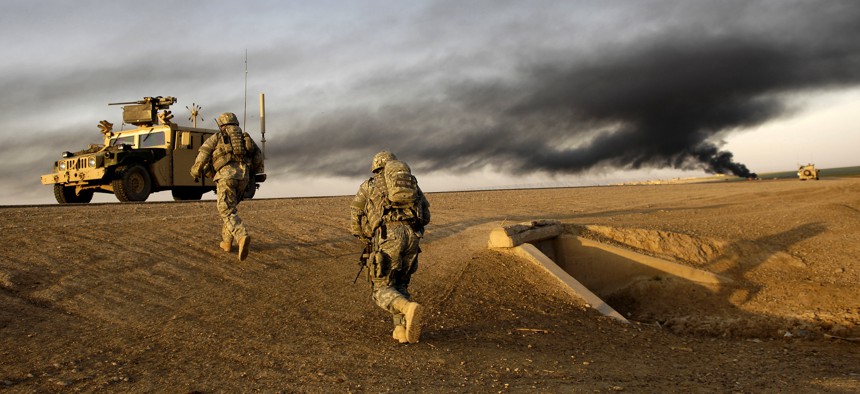 U.S. Army Sgts. Sean Bundy and Dennis First search for IEDs near Al Muradia village, Iraq, in 2007. The smoke is from a controlled IED detonation.