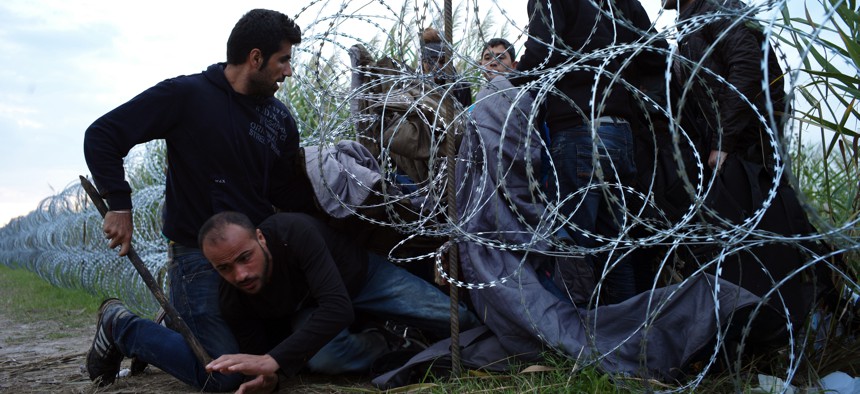Syrian refugees cross into Hungary underneath the border fence on the Hungarian - Serbian border near Roszke, Hungary.