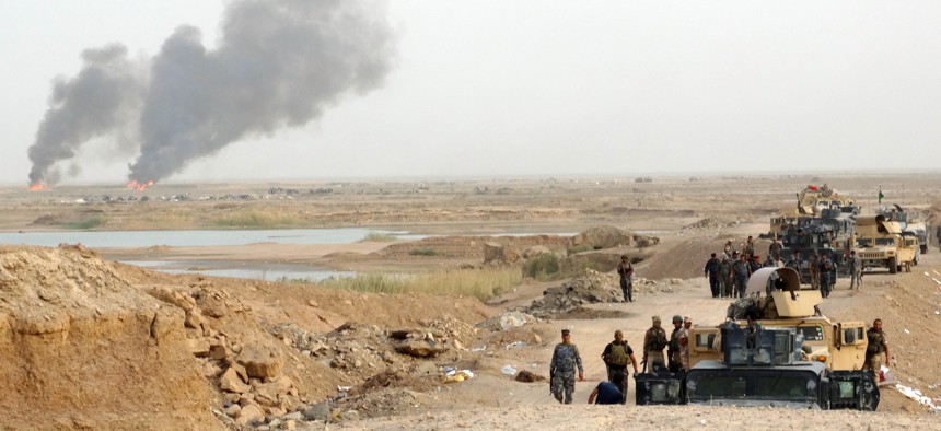In this Thursday, Aug. 6, 2015 photo, smoke rises as Iraqi security forces backed by Shiite and Sunni pro-government fighters bomb Islamic State group positions at the front line in the eastern suburbs of Ramadi, Anbar province, Iraq.