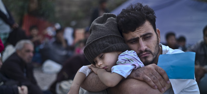 A Syrian refugee child sleeps on his father's arms while waiting at a resting point to board a bus, after arriving on a dinghy from the Turkish coast to the northeastern Greek island of Lesbos, Sunday, Oct. 4 , 2015.