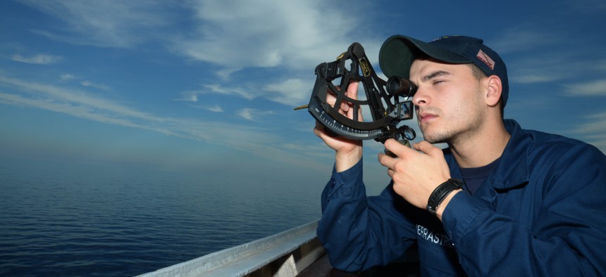 Quartermaster Seaman Pasquale V. Verrastro uses a sextant to find the range of a foreign vessel on the bridge wing of the guided-missile destroyer USS Ramage (DDG 61) in 2014.
