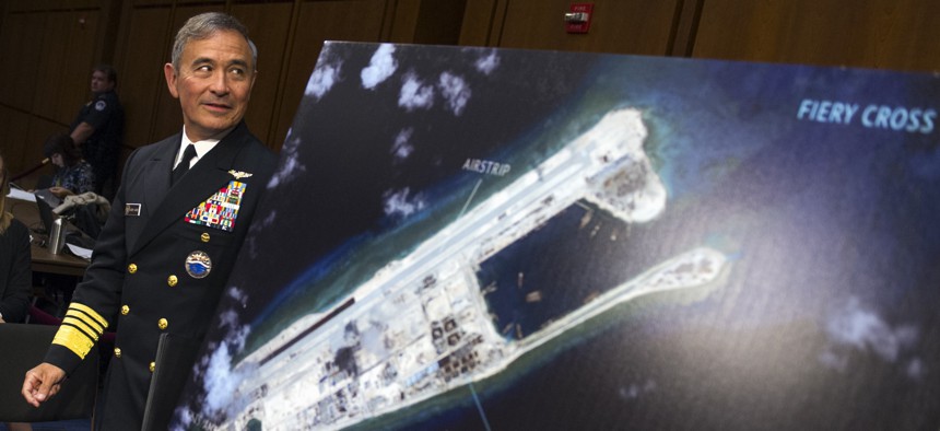Adm. Harry B. Harris, Jr. of U.S. Navy Commander, U.S. Pacific Command walks past a photograph showing an island that China is building on the Fiery Cross Reef in the South China Sea, as the prepares to testify on Capitol Hill, Sept. 17, 2015.