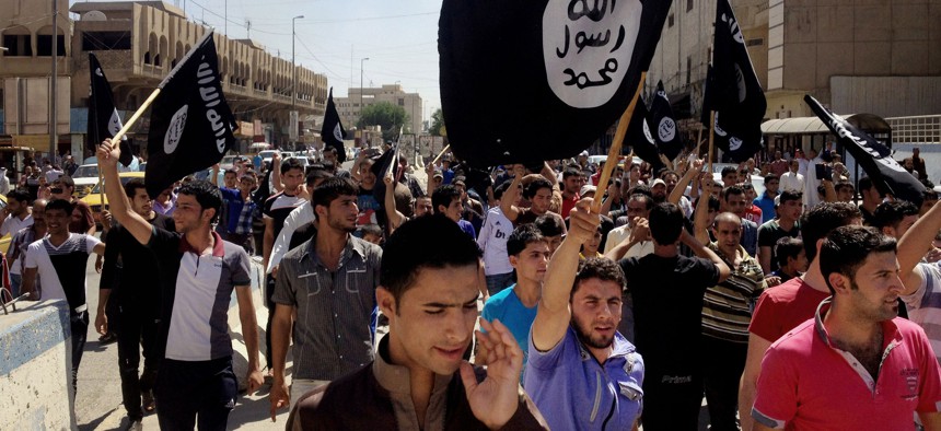 In this Monday, June 16, 2014 file photo, demonstrators chant pro-Islamic State group slogans as they wave the group's flags in front of the provincial government headquarters in Mosul.