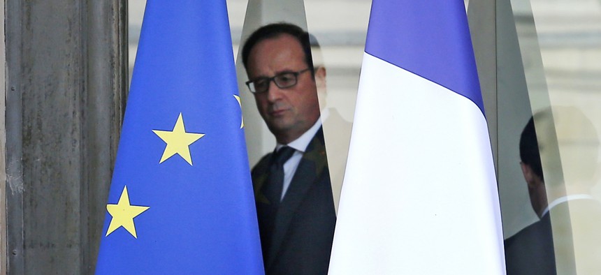 French President Francois Hollande is framed by the French flag, right, and the european flag as he walks through the lobby of the Elysee Palace after the weekly cabinet, in Paris, Wednesday, Nov.18, 2015.