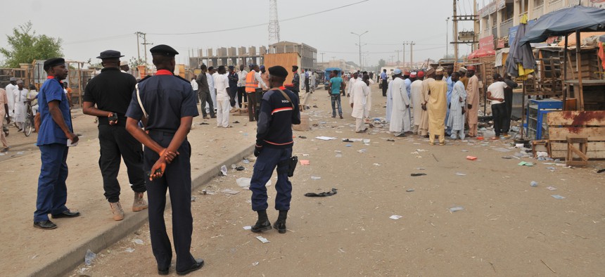 Security officers stand guard at the scene of an explosion at a mobile phone market in Kano, Nigeria.