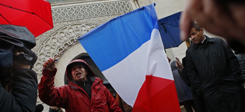 A French Muslim, of Algeria origin, who wants to be named "Cherif" talks to the media, holding a French flag, in front of the Great Mosque of Paris after the Friday priest, in Paris, France, Friday, Nov. 20, 2015 one week after the Paris attacks. 