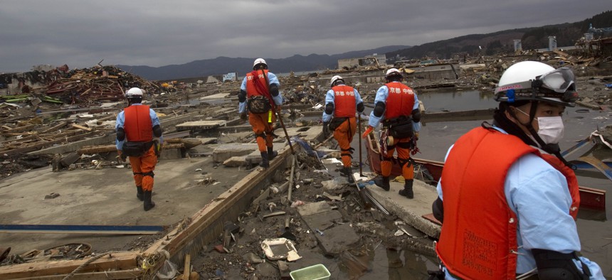 Japanese recovery officials search through the ruins of the leveled city of Minamisanriku, in northeastern Japan, Tuesday March 15, 2011.