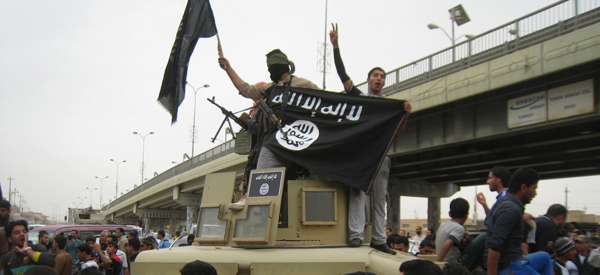 In this Sunday, March 30, 2014, file photo, Islamic State group militants hold up their flag as they patrol in a commandeered Iraqi military vehicle in Fallujah, 40 miles (65 kilometers) west of Baghdad, Iraq.