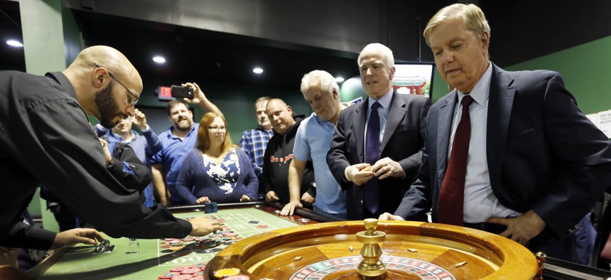 Republican presidential candidate Sen. Lindsey Graham, R-S.C., right, watches as he and Sen. John McCain, R-Ariz., play the roulette wheel at a charitable gaming poker room during a campaign stop at the Manchester Bingo Center and Poker Room Oct. 9, 2015.