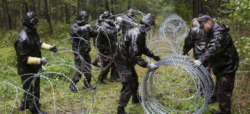 Hungarian soldiers extend spools of razor wire on Slovenian border in Zitkovci, Friday, Sept. 25, 2015.