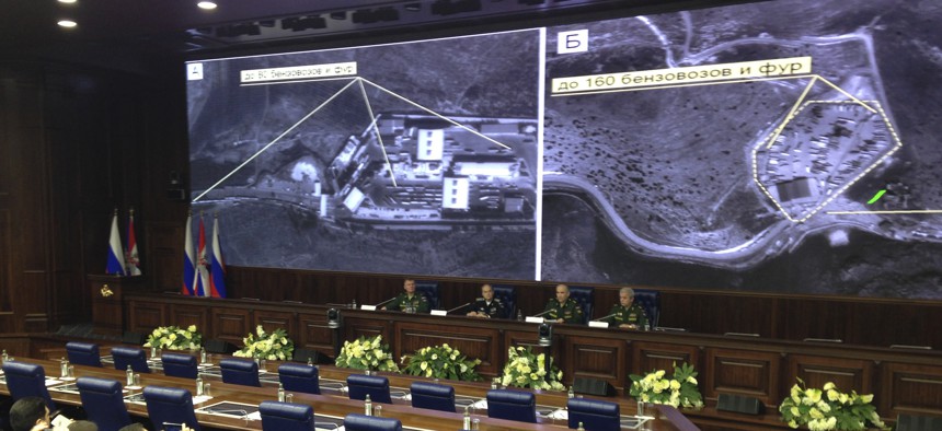 Russian top military officials speak to the media in front of an aerial images they say are oil trucks near Turkey’s border with Syria displayed by the Russian Defense Ministry at a briefing in Moscow, Russia, Wednesday, Dec. 2, 2015.