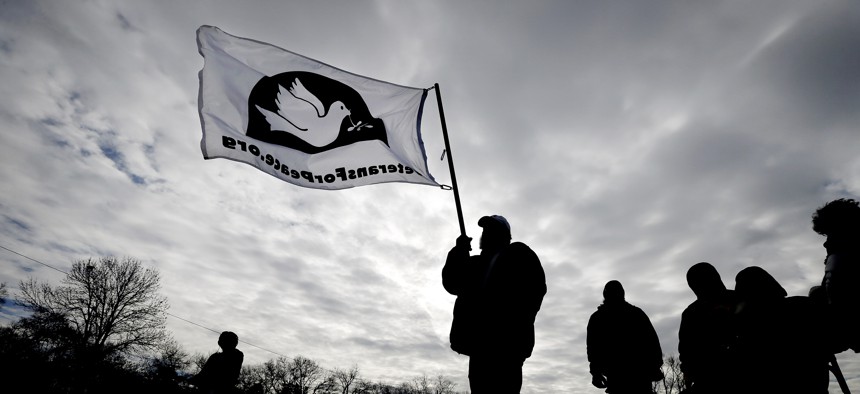 Allen Burney, of Des Moines, Iowa, waves a Veterans for Peace flag during a protest against drone strikes at the Iowa Air National Guard base, Monday, March 17, 2014, in Des Moines, Iowa.
