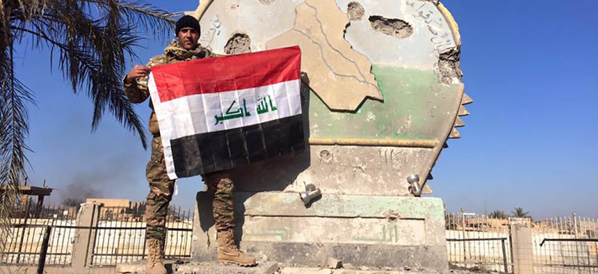 An Iraqi soldier holds a national flag in the government complex in central Ramadi, 70 miles (115 kilometers) west of Baghdad, Iraq, Monday, Dec. 28, 2015.