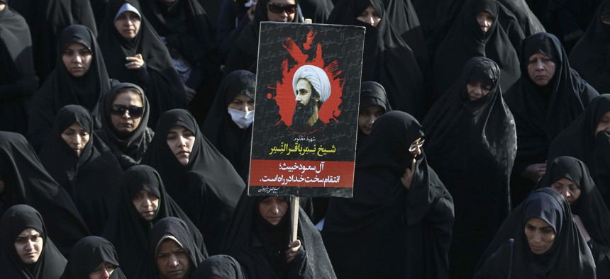 An Iranian woman holds up a poster showing Sheikh Nimr al-Nimr, a prominent opposition Saudi Shiite cleric who was executed last week by Saudi Arabia, in Tehran, Iran, Monday, Jan. 4, 2016.