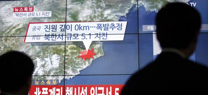 People walk by a screen showing the news reporting about an earthquake near North Korea's nuclear facility, in Seoul, South Korea, Wednesday, Jan. 6, 2016.
