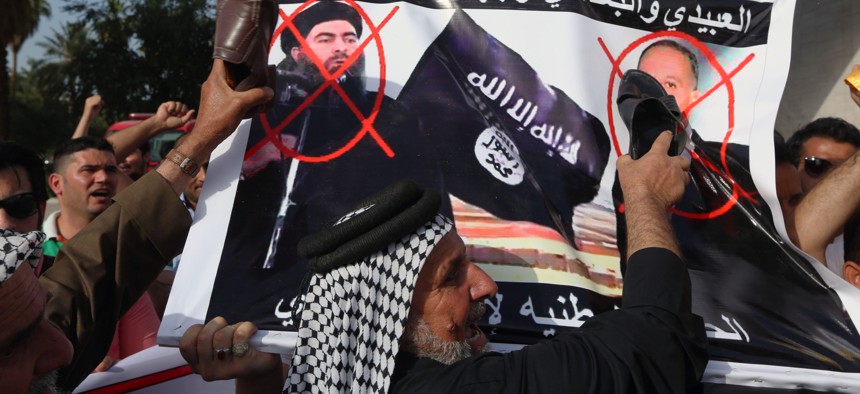 Protesters carry defaced posters of Islamic state leader Abu Bakr al-Baghdadi and Iraqi Defence Minister Khaled al-Obeidi as they chant slogans against the Islamic State group during a protest at Tahrir Square in Baghdad, Iraq, April, 2015.