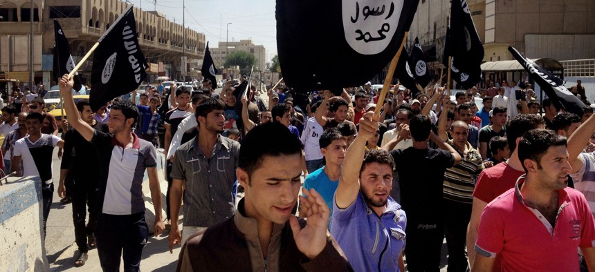 In this June 16, 2014 file photo, demonstrators chant pro-Islamic State group, slogans as they carry the group's flags in front of the provincial government headquarters in Mosul.