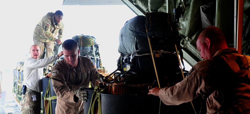 Air Force and Army personnel use a K-loader to load the Joint Precision Air Drop system bundles onto a C-130J Hercules, Bagram AF, Afghanistan, Nov. 27, 2011. 