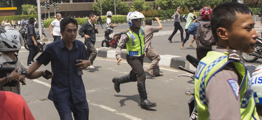 People, including unarmed police officers, flee from the scene after a gun battle broke out following an explosion in Jakarta, Indonesia Thursday, Jan. 14, 2016.