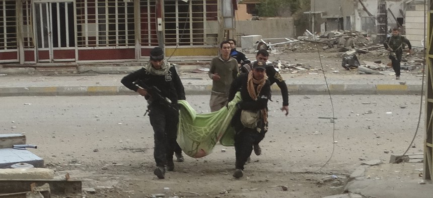 Iraqi security forces and allied Sunni tribal fighters evacuate a badly injured woman after she was shot by Islamic State group fighters as she was trying to cross from neighborhoods in Ramadi, Iraq, Monday, Jan. 4, 2016.