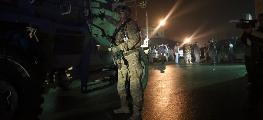 A U.S. soldier stands near his vehicle at the site of a suicide attack near a compound belonging to foreigners in Kabul, Afghanistan, Monday, Jan. 4, 2016. 