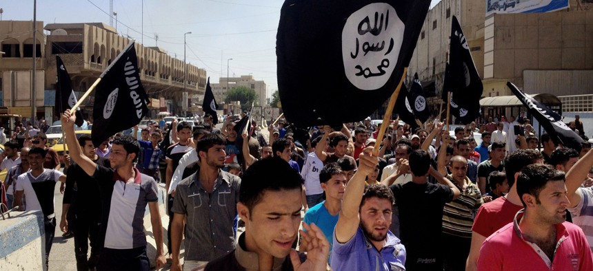 In this Monday, June 16, 2014 file photo, demonstrators chant pro-Islamic State group slogans as they wave the group's flags in front of the provincial government headquarters in Mosul, Iraq. 