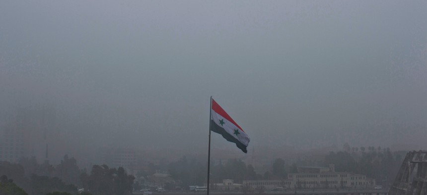 A Syrian national flag waves as heavy fog envelops the capital city of Damascus, Syria, Wednesday, Feb. 24, 2016. 