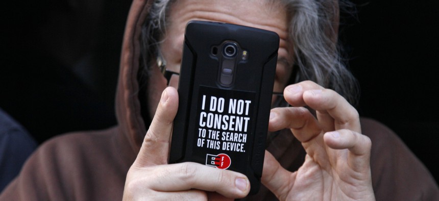 A man holds up his phone during a rally in support of data privacy outside the Apple store Tuesday, Feb. 23, 2016, in San Francisco.