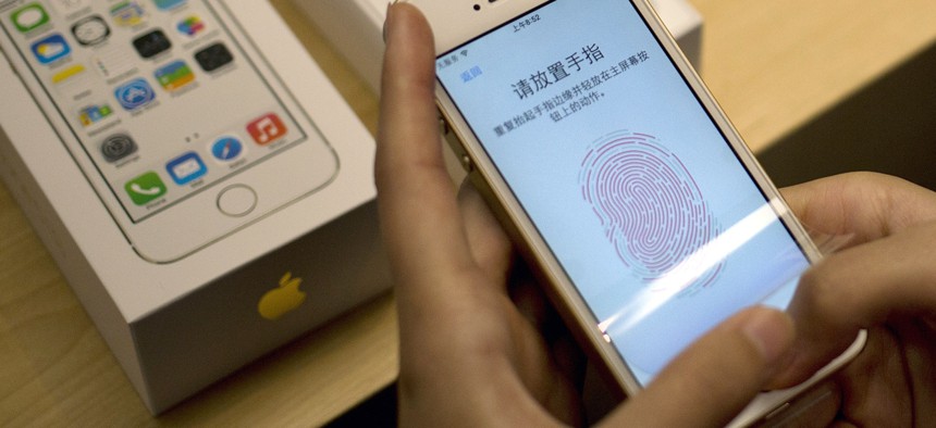 In this Sept. 20, 2013 file photo, a customer configures the fingerprint scanner technology built into the Apple iPhone 5S at an Apple store in Wangfujing shopping district in Beijing.