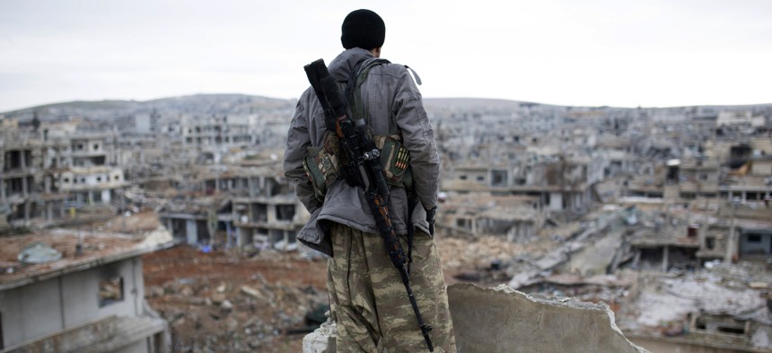 In this Jan. 30, 2015 file photo, a Syrian Kurdish sniper looks at the rubble in the Syrian city of Ain al-Arab, also known as Kobani. 