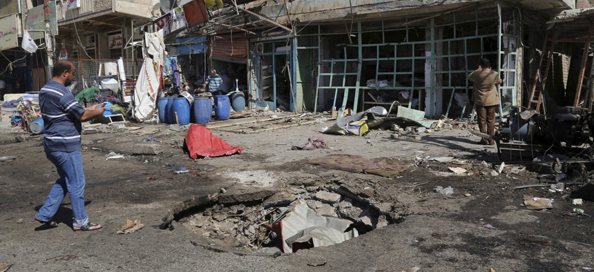 A civilian inspects a crater caused by a car bomb explosion in Baghdad, Iraq, Friday, Sept. 12, 2014.