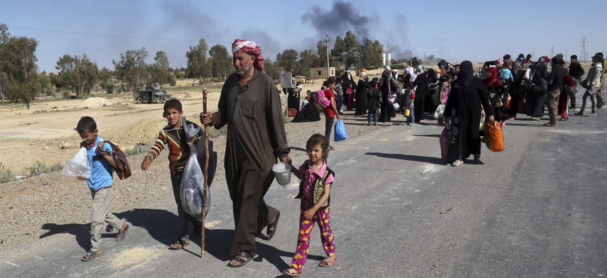 People flee their homes during clashes between Iraqi security forces and Islamic State group in Hit, 85 miles (140 kilometers) west of Baghdad, Iraq, Monday, April 4, 2016.
