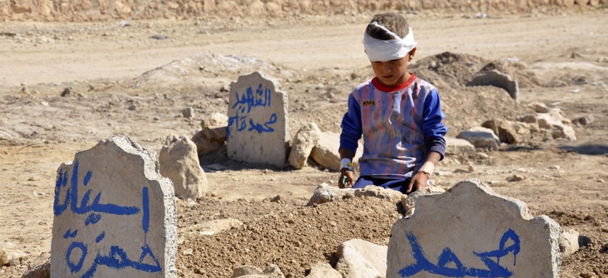 Ali Hamza, 8, sits at the graves of his brother, Mohammed, and sister Asinat, who were killed at their school when a suicide car bomb attack near Qabak elementary school in the Shiite Turkomen village of Qabak, just outside of in Tal Afar, Oct. 7, 2013.