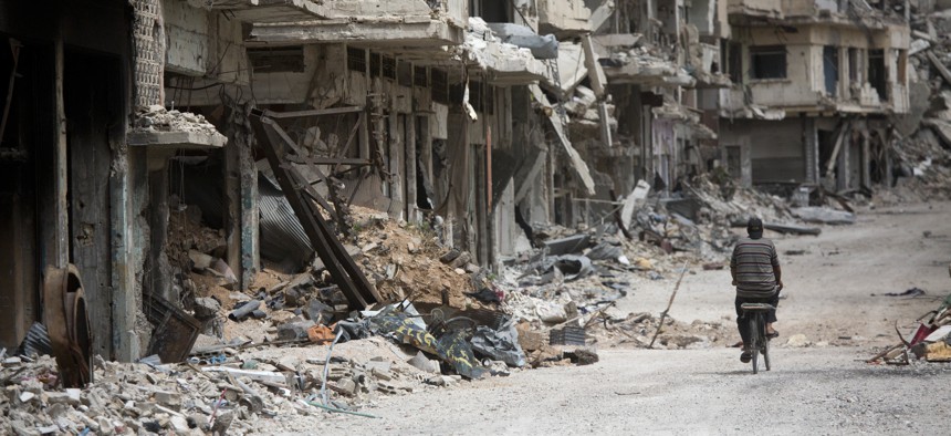A man rides a bicycle through a devastated part of Homs, Syria, June 5, 2014.
