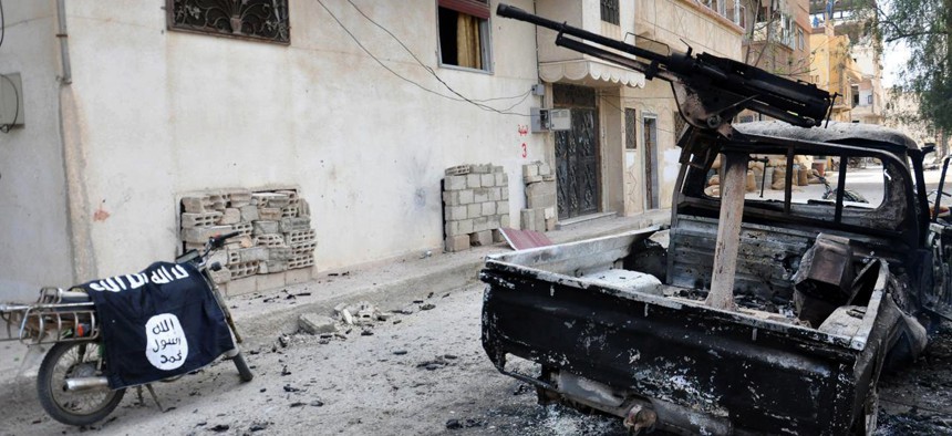 In this photo released on Sunday March 27, 2016, by the Syrian official news agency SANA, a burned vehicle with machine gun is seen next to a motorcycle draped with the Islamic State group flag, in the ancient city of Palmyra, central Syria.