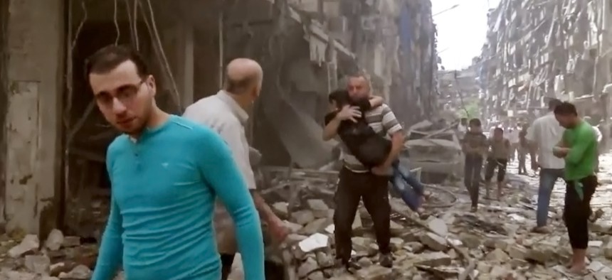 A man carries a child after airstrikes hit Aleppo, Syria, Apr. 28, 2016.