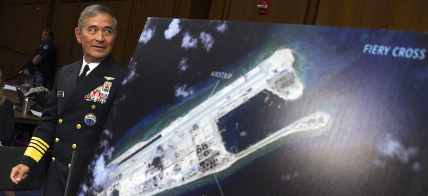 Adm. Harry Harris, commander of U.S. Pacific Command, walks past a photograph showing an artificial island China has built on the Fiery Cross Reef before an October 2015 congressional hearing.
