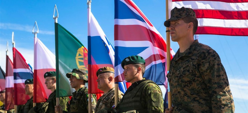 U.S. Marine Sgt. Steven Mashburn, a squad leader with Black Sea Rotational Force, right, holds the American flag during the opening ceremony for NATO's Exercise Saber Strike at the Pabrade Training Area, Lithuania, June 8, 2015.