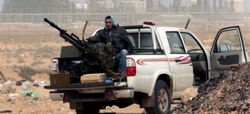 An anti-government rebel sits with an anti-aircraft weapon in front an oil refinery in Ras Lanouf, eastern Libya, March 5, 2011.
