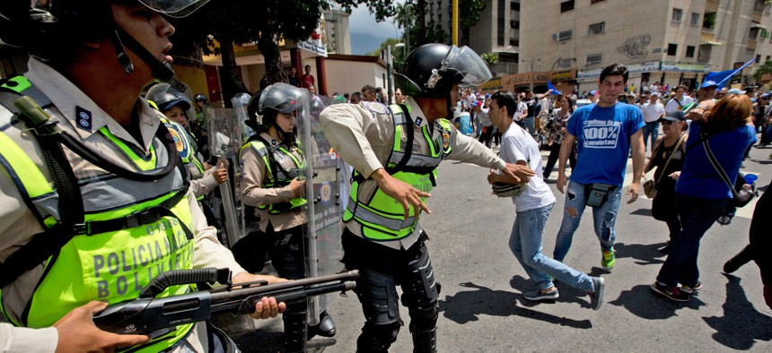 Bolivarian National Police officer try to disperse demonstrators during an opposition protest in Caracas, Venezuela, Friday, Sept. 16, 2016.