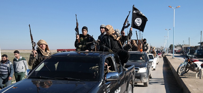 Islamic State militants pass by a convoy in Tel Abyad, northeast Syria, May 4, 2015. 