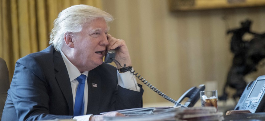 President Donald Trump speaks on the phone with Russian President Vladimir Putin, Saturday, Jan. 28, 2017, in the Oval Office at the White House in Washington.