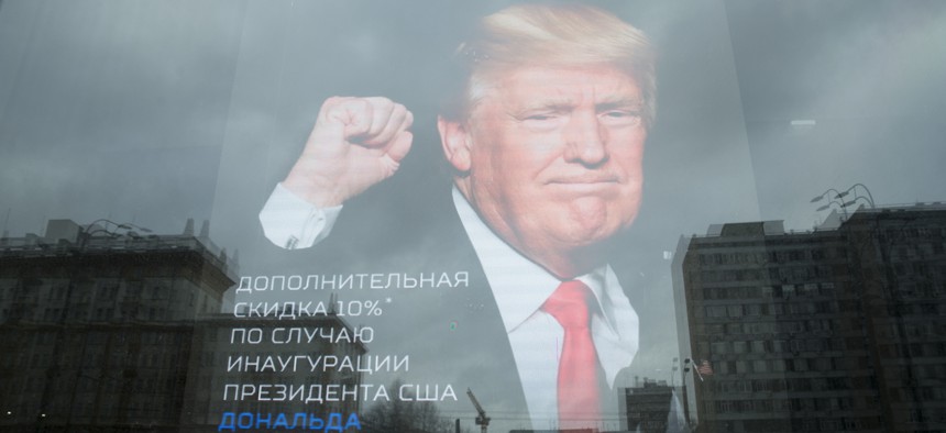 The U.S. Embassy building is reflected in a window of a Russian military outerwear shop "Armia Rossii" (Russian Army) displaying a poster of Donald Trump, in downtown Moscow, Russia, Friday, Jan. 20, 2017.