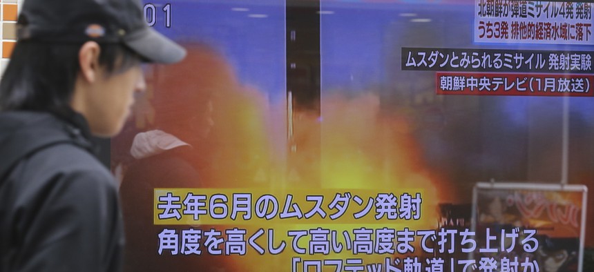 A man walks past a screen showing a TV news on North Korea's missile firing, in Tokyo, Monday, March 6, 2017. 