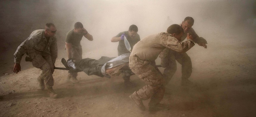 United States Marines run through dust kicked up by a Blackhawk helicopter as they rush a colleague wounded in an IED strike for evacuation near Sangin, Helmand Province, Afghanistan, on May 10, 2011.