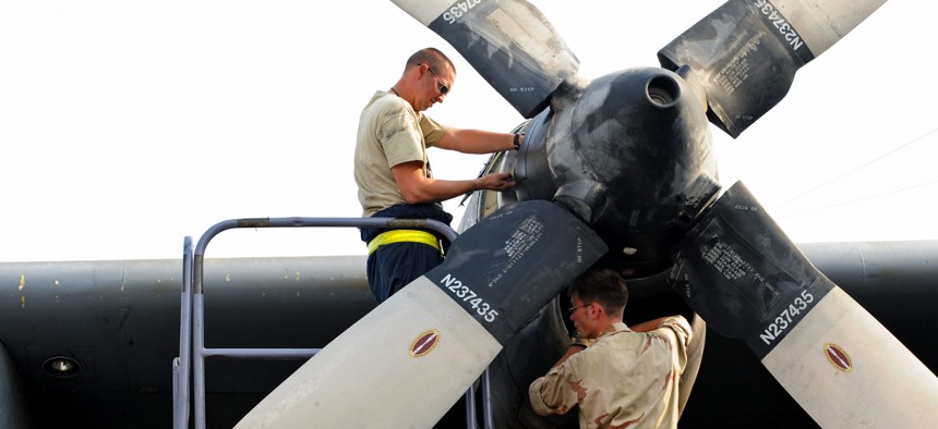 U.S. Air Force Tech. Sgt. Christopher Chadwell, left, performs a propeller hydraulic fluid level check while Staff Sgt. William Aker does an engine inlet inspection on a C-130E Hercules aircraft somewhere in southwest Asia on Aug.11, 2010.