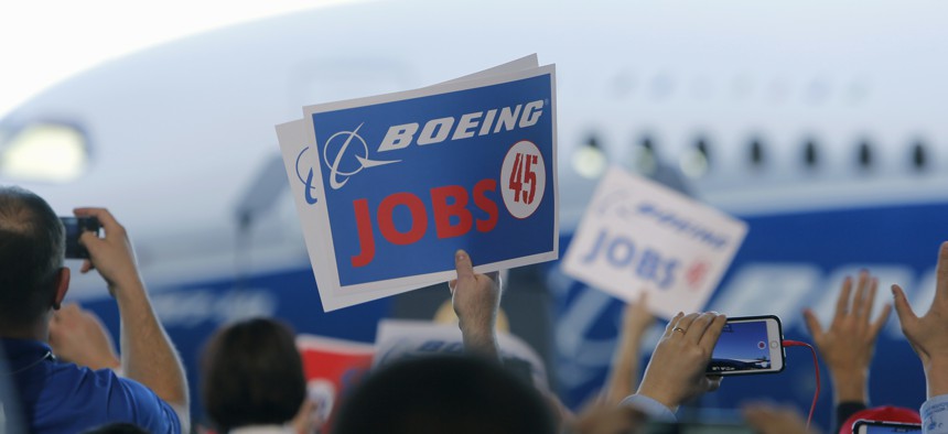 Boeing employees hold up signs as President Donald Trump speaks on Feb. 17, at company factory in North Charleston, S.C. 